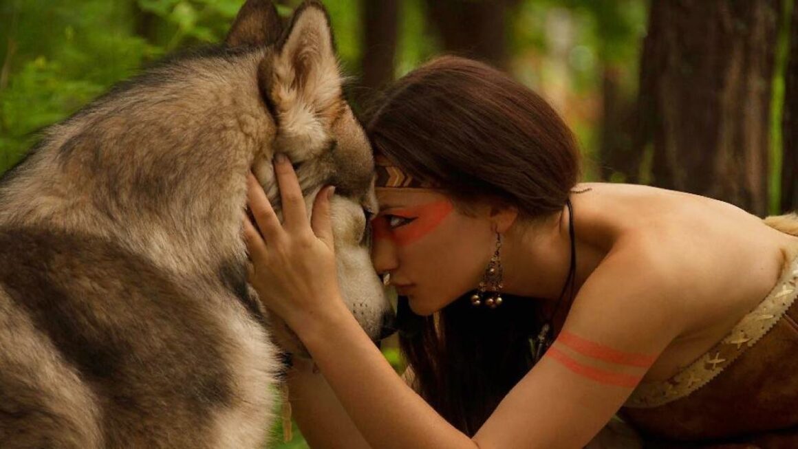 A woman discovering her inner animal by kissing a wolf in the woods.