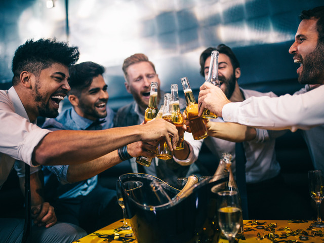 A group of men adhering to drinking etiquette as they toast champagne at a party.