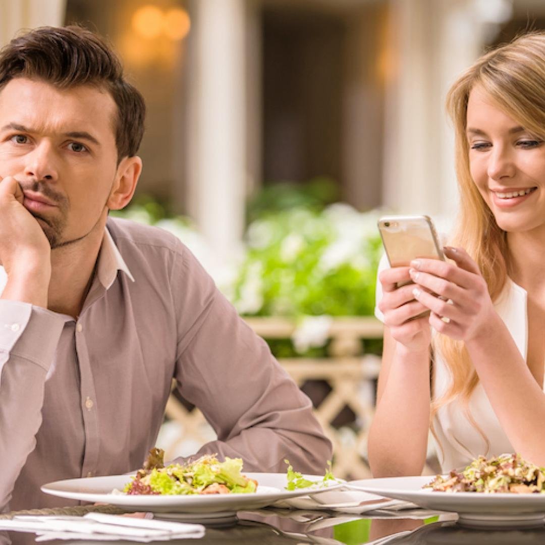 A couple discussing deal-breakers while using their phones.