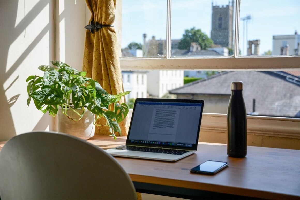 Top Accessories and Gadgets To Make Working From Home Easier - a laptop on a desk in front of a window.