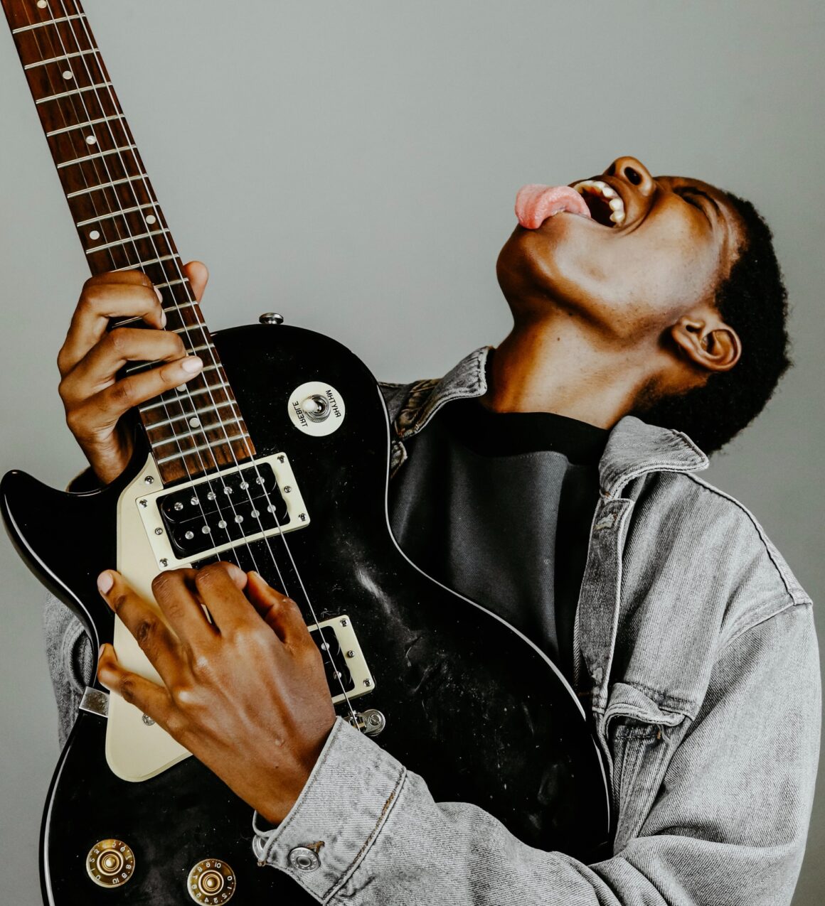 A black man playing an electric guitar with his tongue out, showcasing his incredible talent in the realm of blues or jazz music. This captivating image is a testament to the rich and vibrant history of