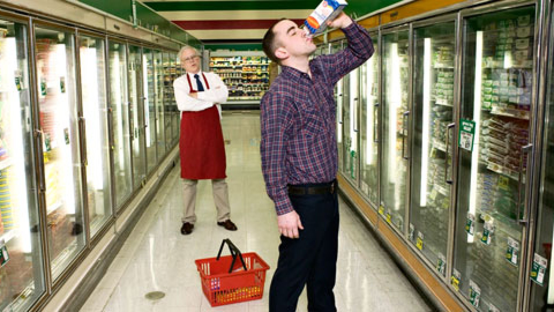 A man standing in a grocery store holding a bottle of water, proving that the customer is not always right.
