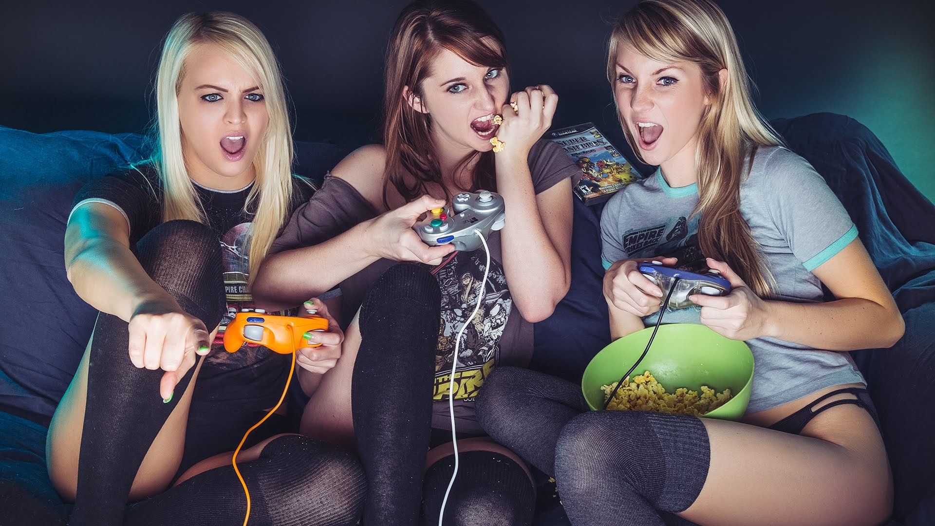 Three girls sitting on a couch with video game controllers.