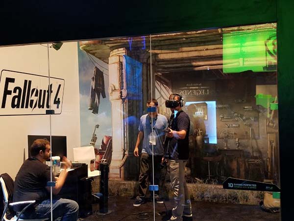 A group of people standing in front of a booth with a fallout 4 sign.